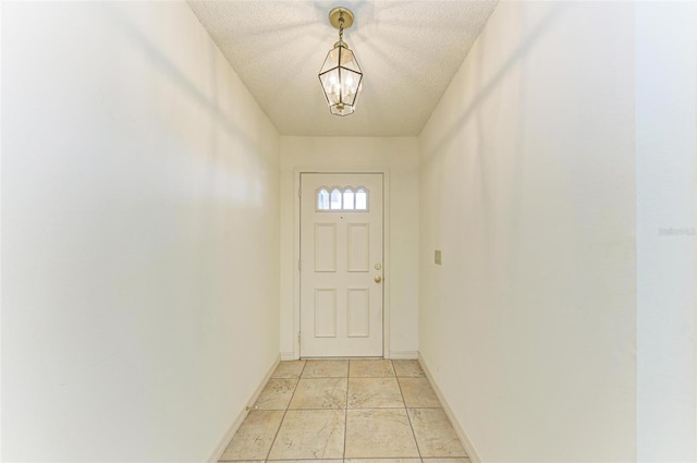 doorway with an inviting chandelier, a textured ceiling, and light tile floors