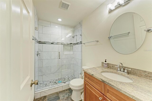 bathroom featuring a shower with shower door, vanity, toilet, and tile floors