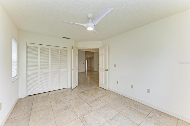 unfurnished bedroom with a textured ceiling, a closet, ceiling fan, and light tile floors