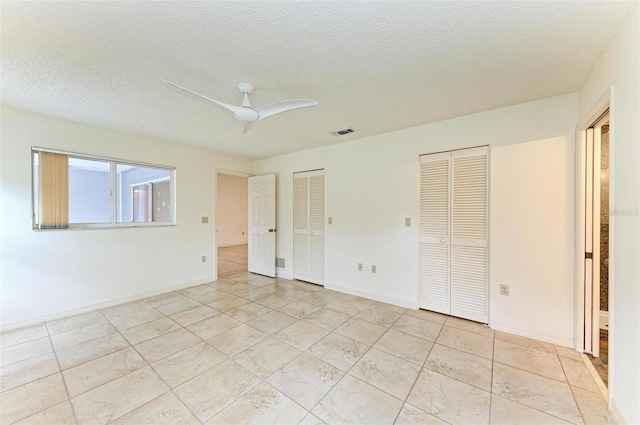 unfurnished bedroom with two closets, ceiling fan, and light tile floors