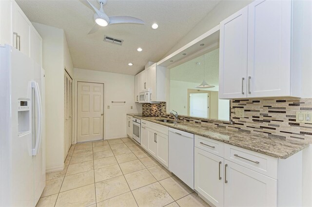 kitchen featuring sink, white appliances, ceiling fan, light stone countertops, and white cabinets