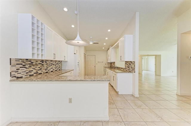 kitchen with kitchen peninsula, tasteful backsplash, white cabinetry, and light tile floors