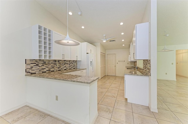 kitchen featuring hanging light fixtures, light stone counters, backsplash, and white cabinetry