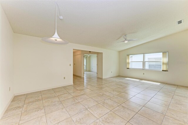 empty room with a textured ceiling, lofted ceiling, light tile flooring, and ceiling fan