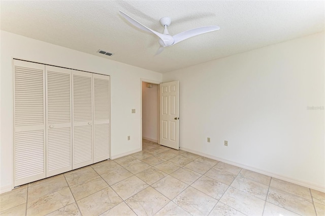 unfurnished bedroom featuring ceiling fan, a closet, a textured ceiling, and light tile flooring