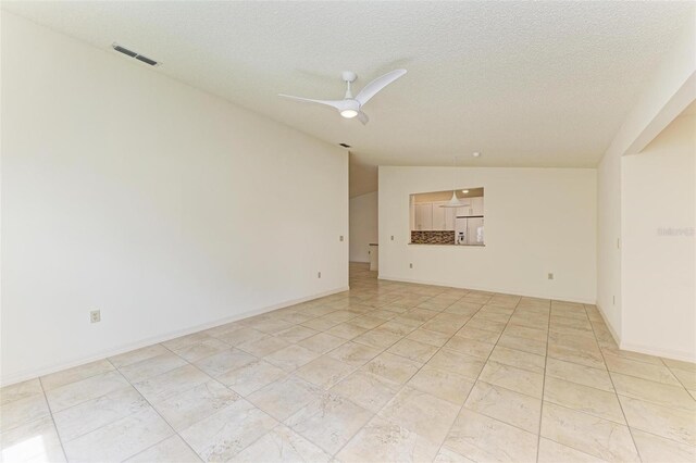 spare room featuring ceiling fan, lofted ceiling, and a textured ceiling