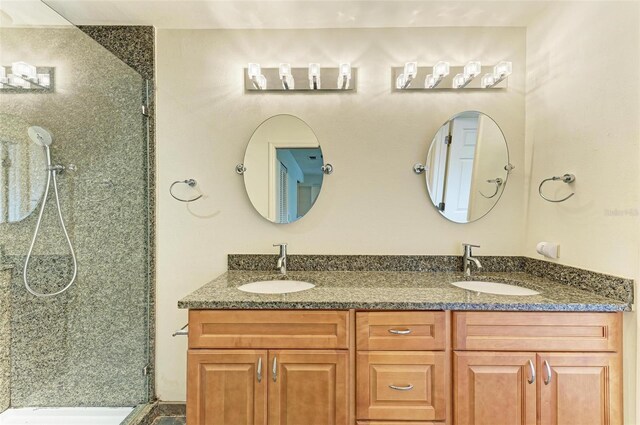 bathroom featuring a shower with door, dual sinks, and oversized vanity