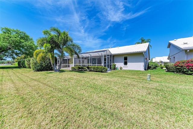 back of property with glass enclosure and a lawn