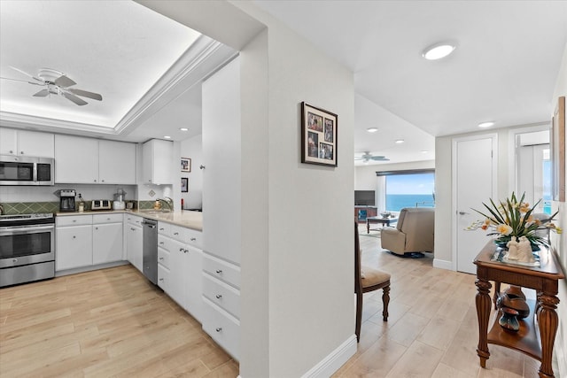 kitchen with appliances with stainless steel finishes, white cabinetry, ceiling fan, and light wood-type flooring