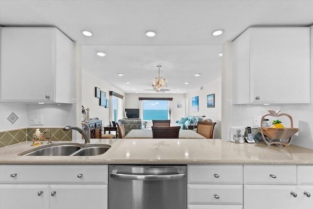 kitchen with sink, stainless steel dishwasher, backsplash, light stone countertops, and white cabinetry