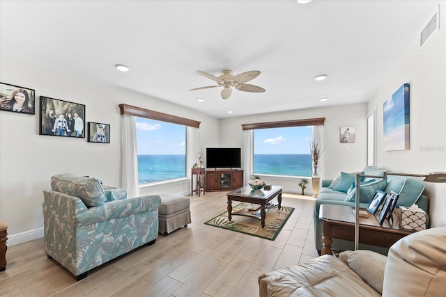 living room with plenty of natural light, ceiling fan, and a water view