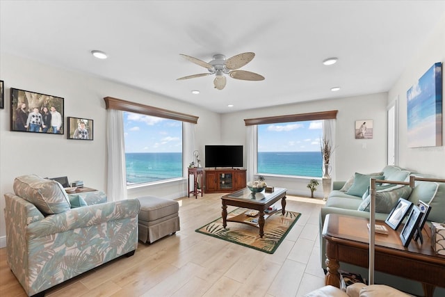 living room featuring a water view, ceiling fan, and a wealth of natural light