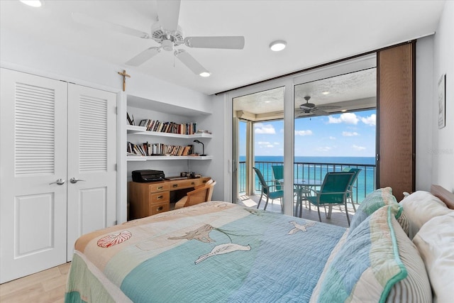 bedroom featuring a closet, access to outside, light hardwood / wood-style floors, and a water view