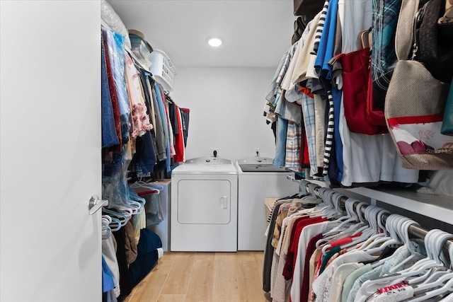 walk in closet with separate washer and dryer and light wood-type flooring