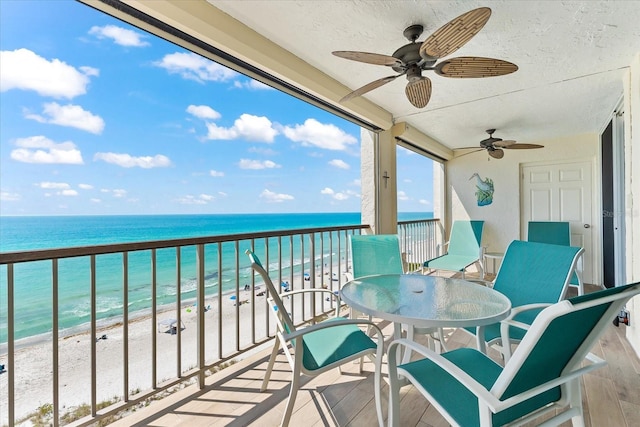 balcony with a water view, ceiling fan, and a view of the beach