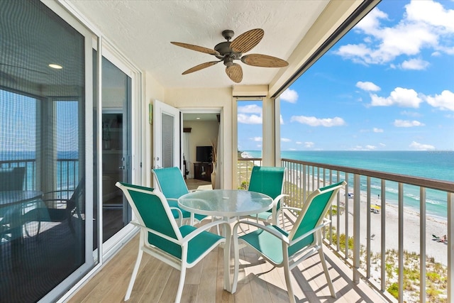 balcony featuring a water view, a beach view, and ceiling fan