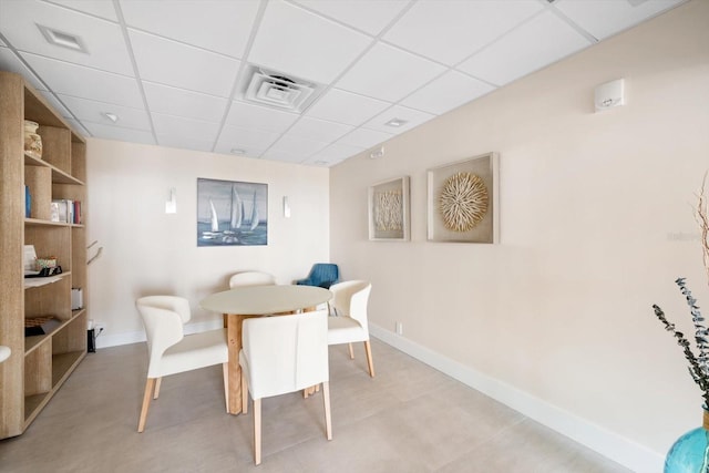 dining area with a paneled ceiling and light tile flooring