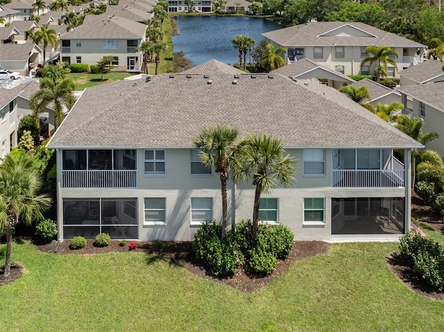 rear view of property featuring a lawn and a water view