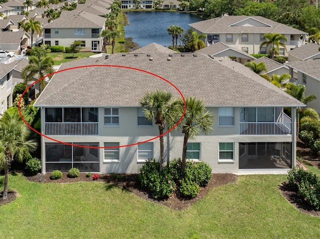 back of house with a lawn and a water view