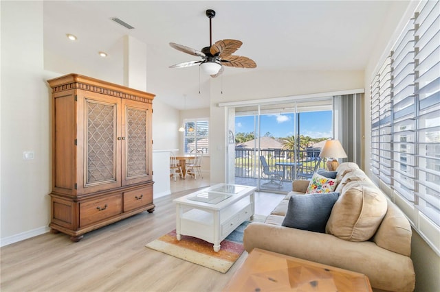 living room with ceiling fan, light hardwood / wood-style floors, and vaulted ceiling