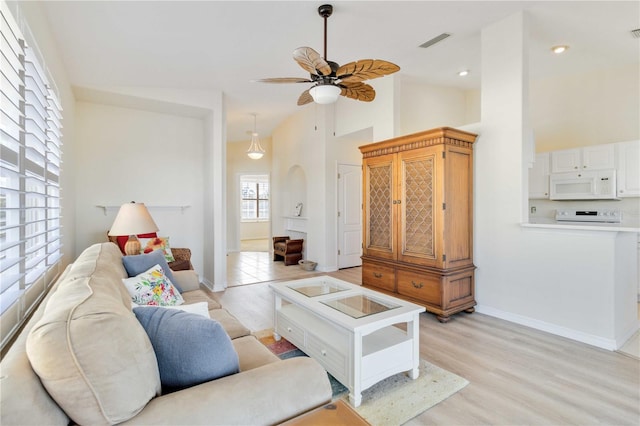 living room featuring ceiling fan, high vaulted ceiling, and light wood-type flooring