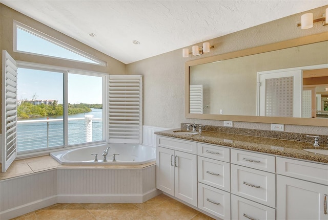 bathroom featuring tile flooring, dual bowl vanity, a bathing tub, and lofted ceiling