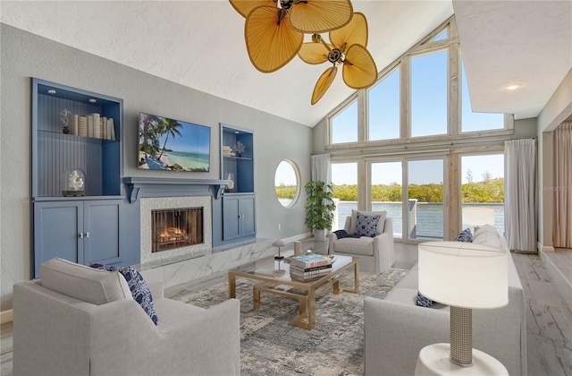 living room with light hardwood / wood-style floors, ceiling fan, high vaulted ceiling, and a fireplace