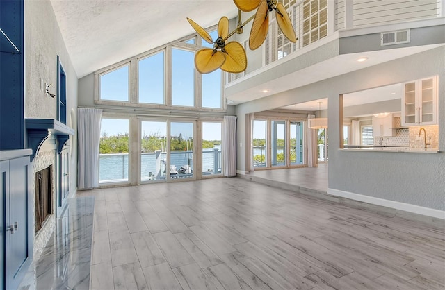 unfurnished living room with high vaulted ceiling, light hardwood / wood-style floors, and ceiling fan