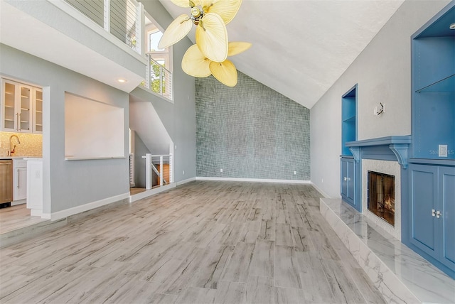 unfurnished living room featuring high vaulted ceiling, sink, light hardwood / wood-style flooring, and ceiling fan