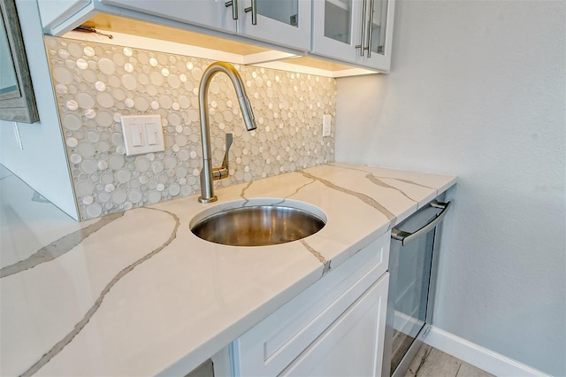 interior space with light stone counters, light hardwood / wood-style flooring, white cabinetry, sink, and stainless steel dishwasher