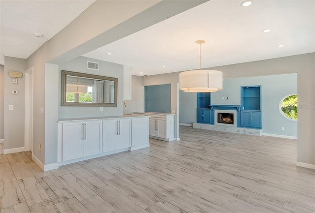 kitchen featuring hanging light fixtures, light wood-type flooring, and white cabinetry