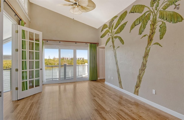 empty room with plenty of natural light, high vaulted ceiling, and light wood-type flooring