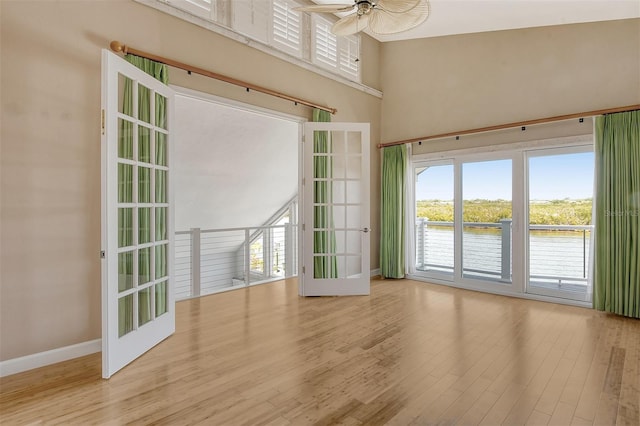 empty room with plenty of natural light, a towering ceiling, and light wood-type flooring