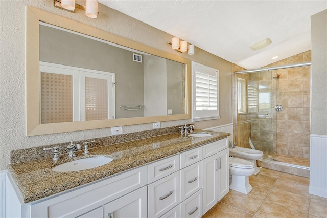 bathroom featuring vanity with extensive cabinet space, dual sinks, toilet, and a shower with door