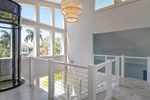 corridor featuring light tile flooring, a high ceiling, a chandelier, and a wealth of natural light