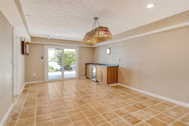 tiled empty room with bar and a textured ceiling