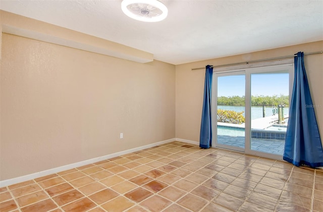 unfurnished room featuring tile floors and a water view