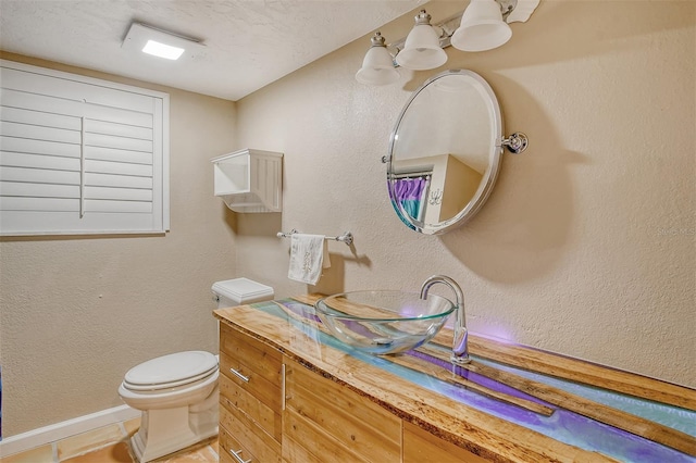 bathroom with a textured ceiling, vanity, and toilet