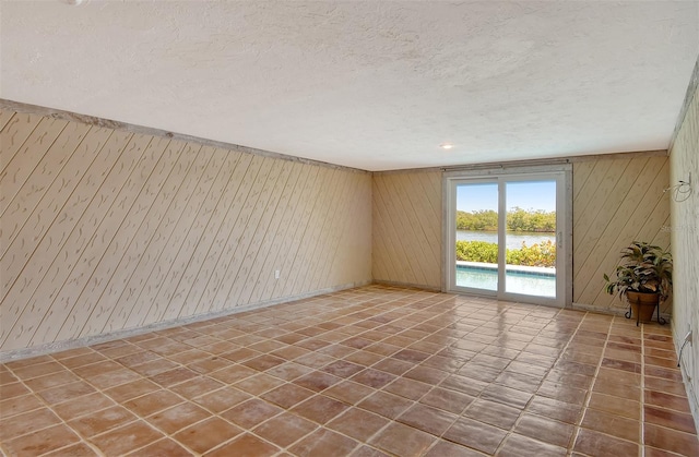 spare room featuring a textured ceiling and dark tile flooring