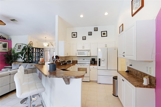 kitchen with white appliances, sink, light tile floors, a breakfast bar area, and white cabinetry