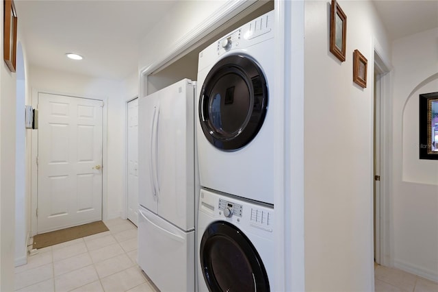 laundry area featuring light tile flooring and stacked washing maching and dryer