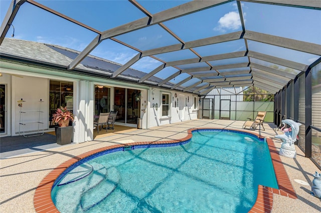 view of pool with glass enclosure and a patio