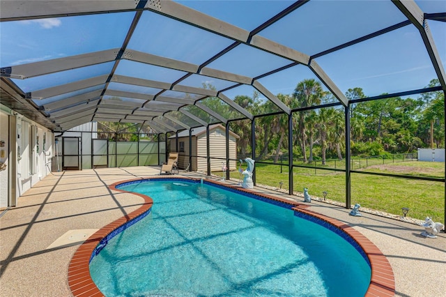 view of pool with glass enclosure, a yard, a patio area, and a shed