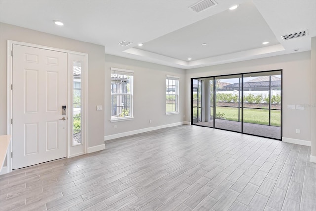 foyer with light hardwood / wood-style floors and a tray ceiling