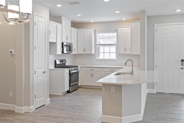 kitchen featuring white cabinets, backsplash, appliances with stainless steel finishes, and sink