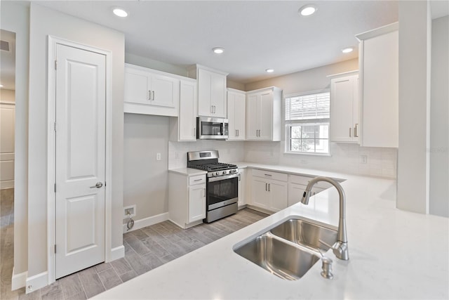 kitchen featuring white cabinetry, appliances with stainless steel finishes, light hardwood / wood-style floors, sink, and tasteful backsplash