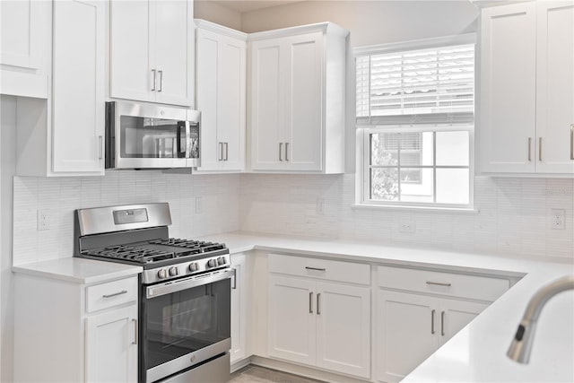 kitchen with backsplash, white cabinetry, and appliances with stainless steel finishes