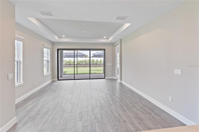 spare room featuring a raised ceiling and light hardwood / wood-style floors