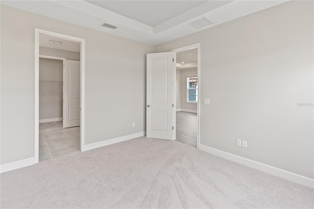 unfurnished bedroom with a closet, light carpet, and a spacious closet