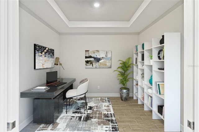 office area with a tray ceiling and light wood-type flooring